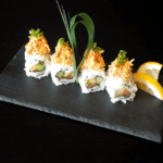 Sushi on a slate plate with lemon wedges.