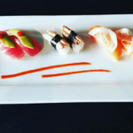 A white plate with a variety of sushi on it.